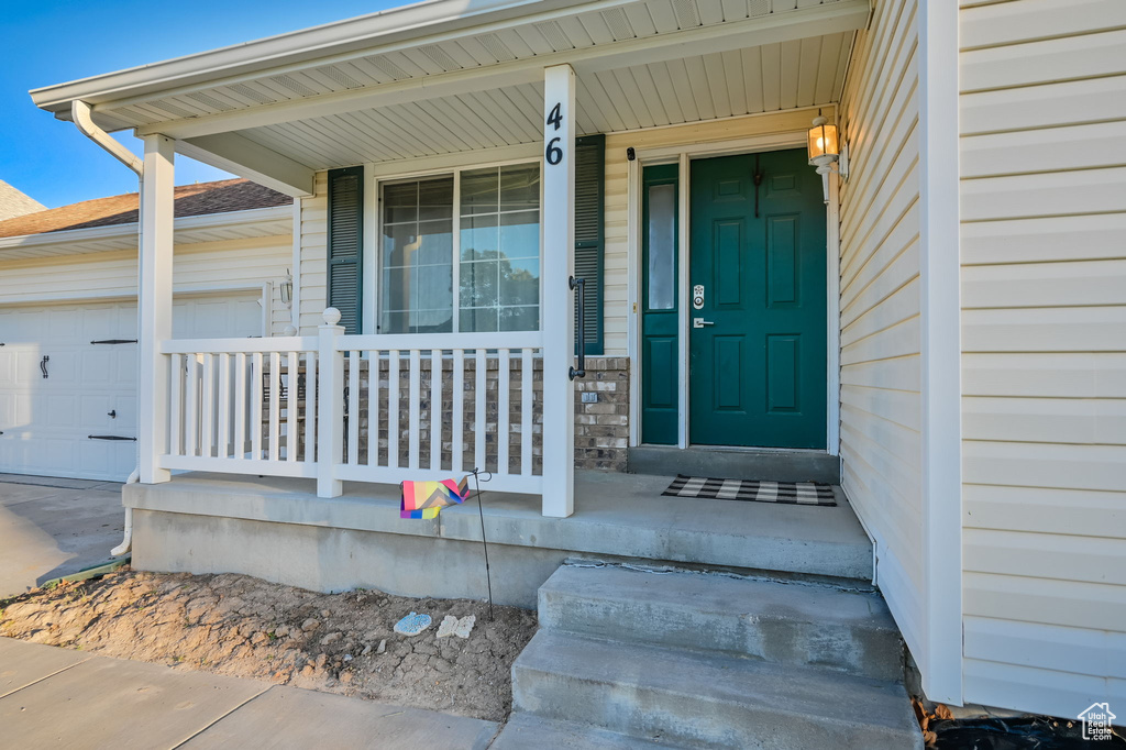 Doorway to property featuring a porch and a garage