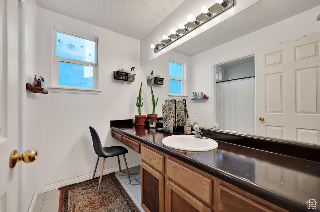 Bathroom with vanity with extensive cabinet space, a textured ceiling, and tile floors