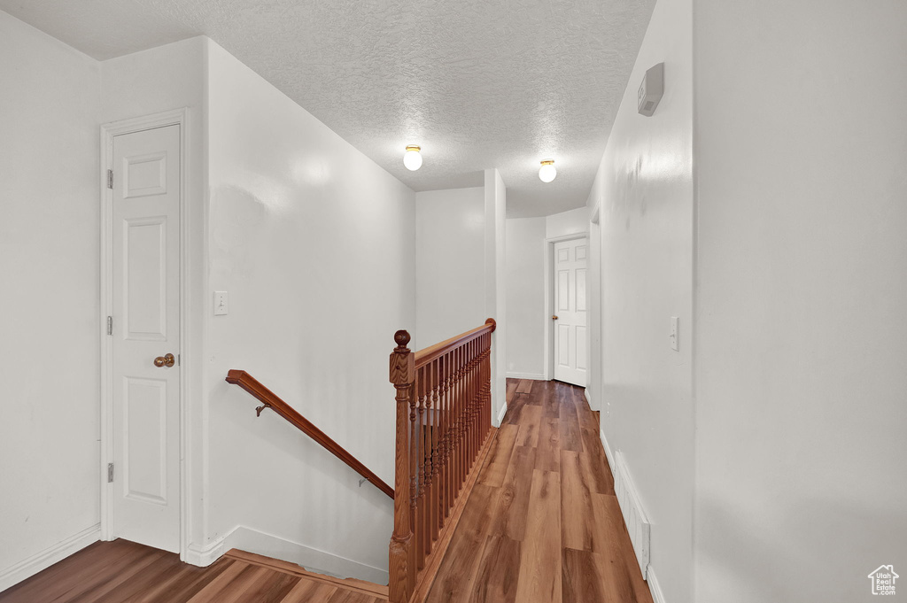 Corridor featuring a textured ceiling and wood-type flooring