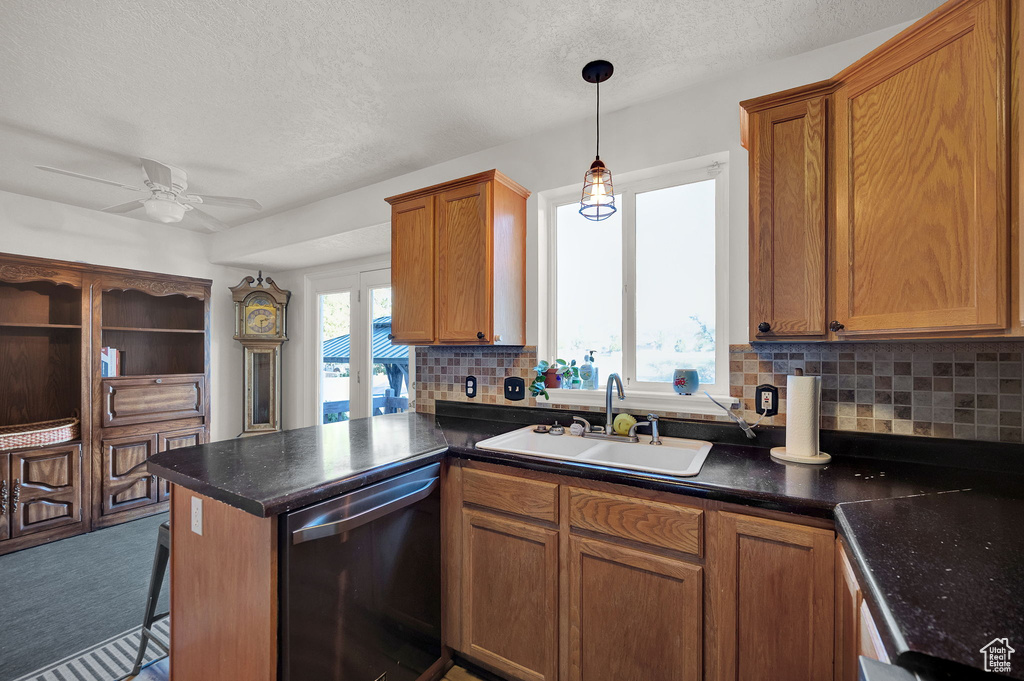 Kitchen featuring dishwasher, ceiling fan, sink, carpet floors, and pendant lighting