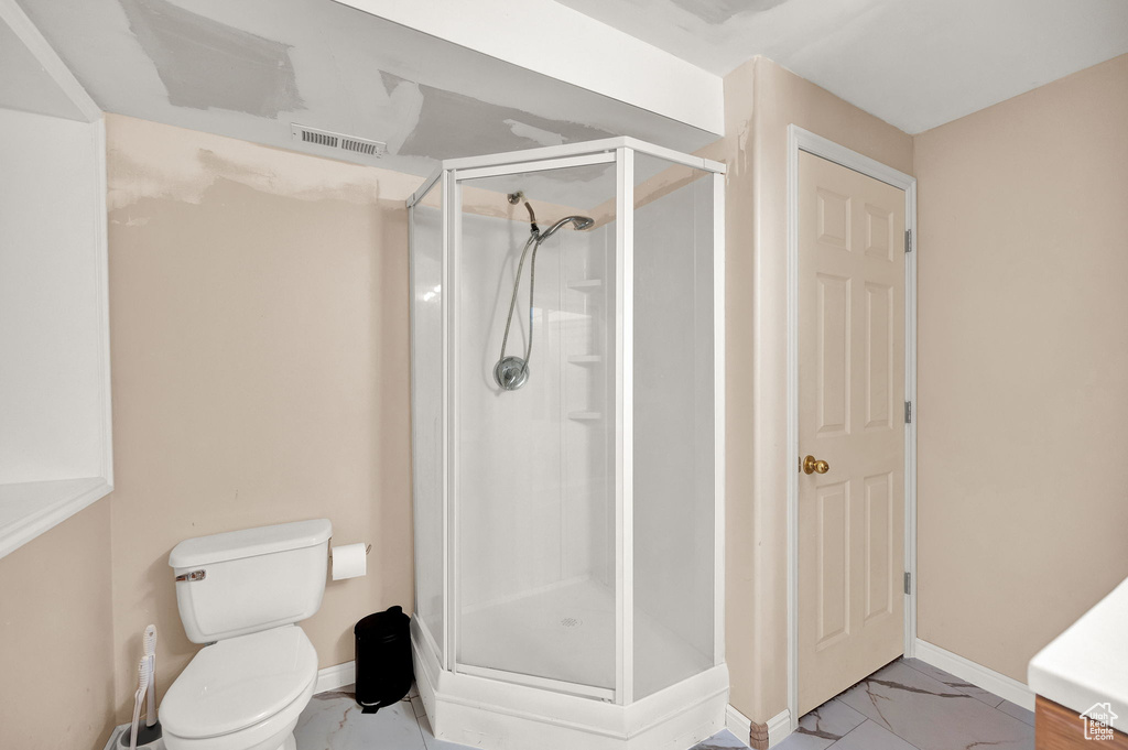 Bathroom featuring vanity, toilet, tile floors, and a shower with door