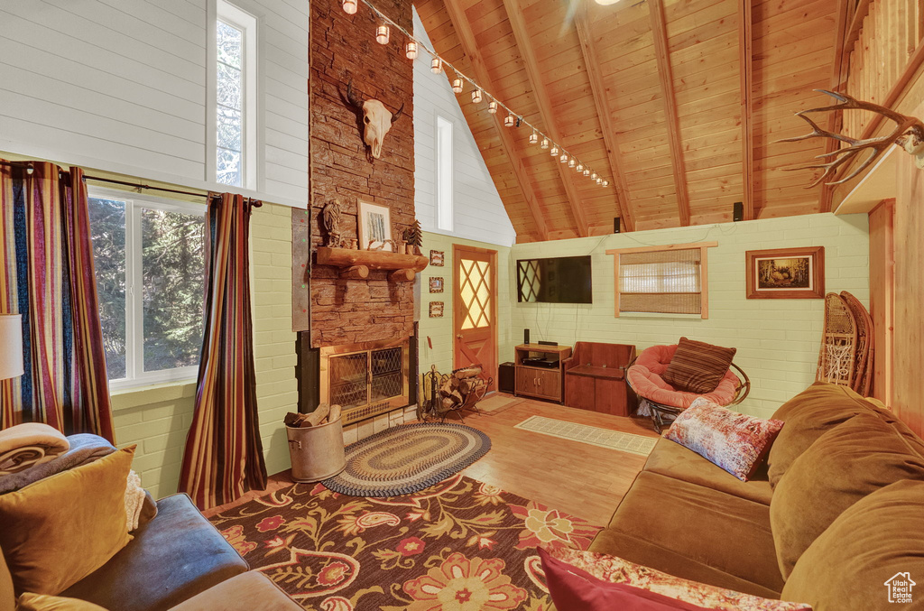 Living room with a fireplace, hardwood / wood-style flooring, wood ceiling, high vaulted ceiling, and beamed ceiling