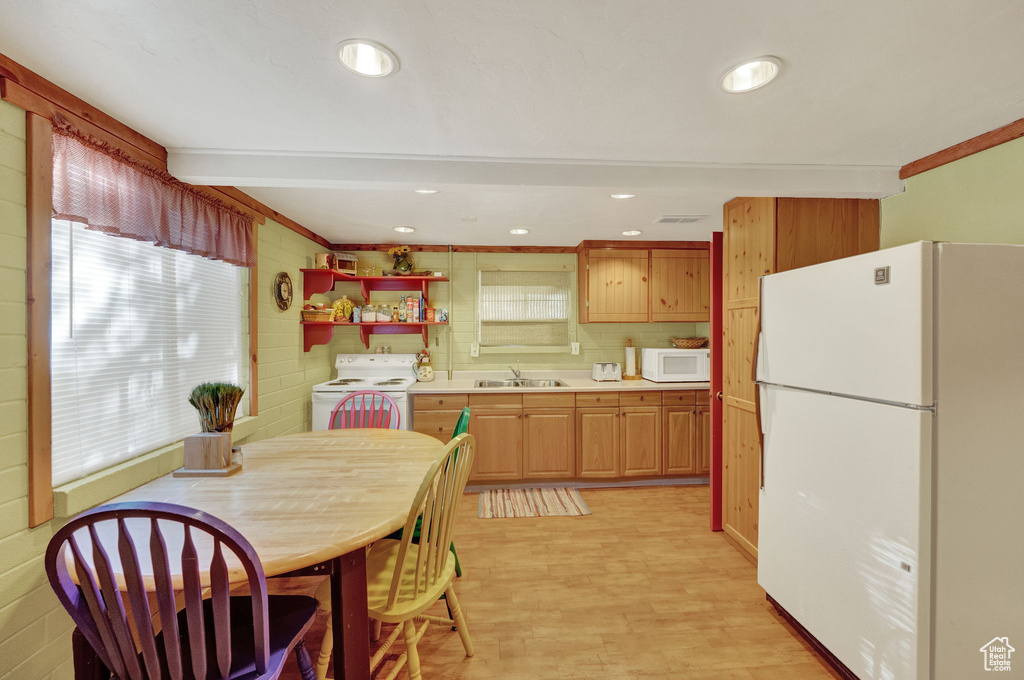 Kitchen with a wealth of natural light, sink, light hardwood / wood-style flooring, and white appliances