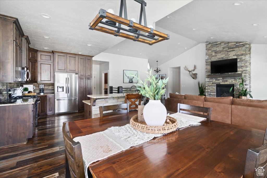 Dining room featuring high vaulted ceiling, a fireplace, and dark hardwood / wood-style floors