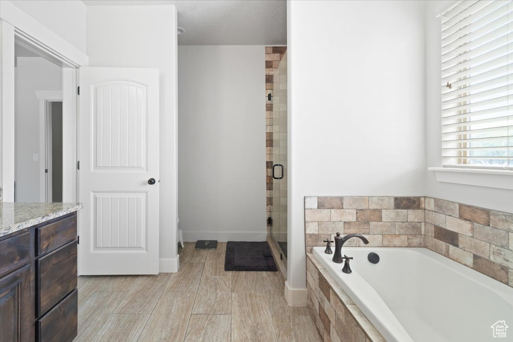 Bathroom featuring tile flooring, separate shower and tub, and vanity