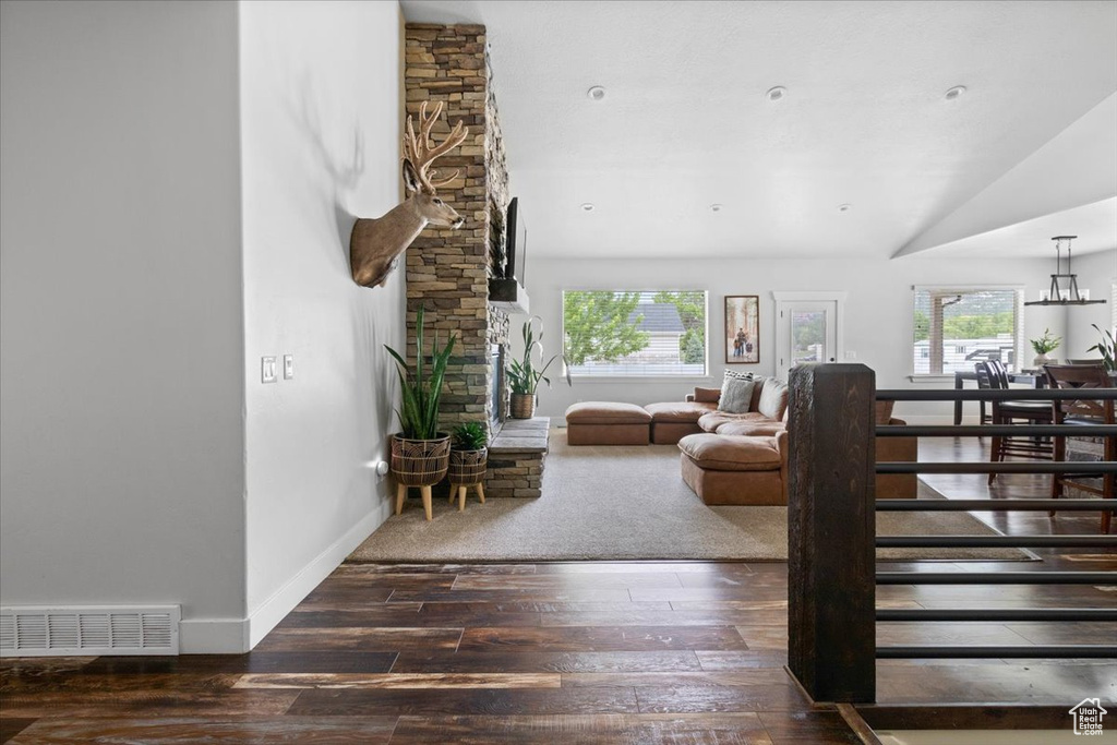 Carpeted living room featuring a stone fireplace, a healthy amount of sunlight, and lofted ceiling