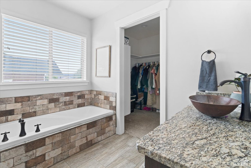 Bathroom featuring tile flooring, tiled tub, and vanity