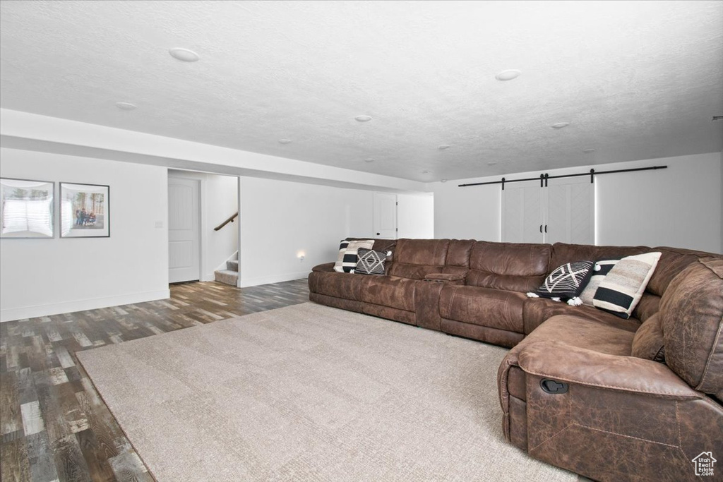 Living room with a barn door, a textured ceiling, and hardwood / wood-style floors