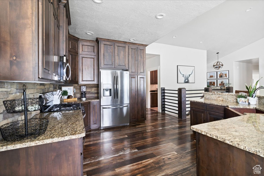 Kitchen featuring range with gas cooktop, stainless steel fridge, backsplash, and dark wood-type flooring