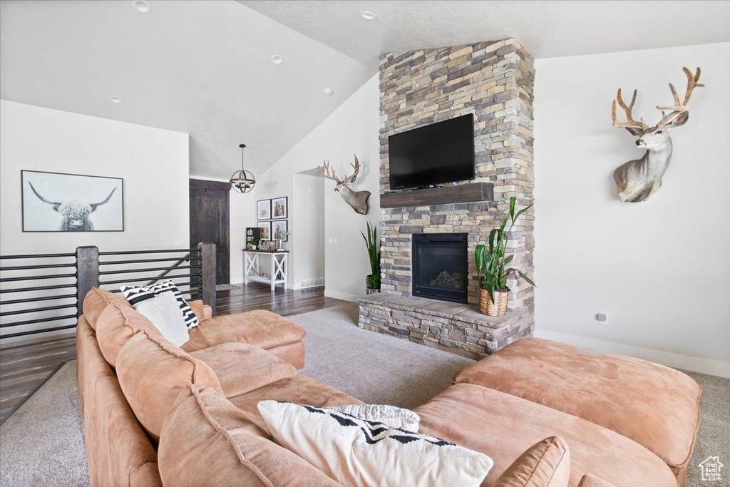 Living room featuring a stone fireplace, high vaulted ceiling, and hardwood / wood-style flooring