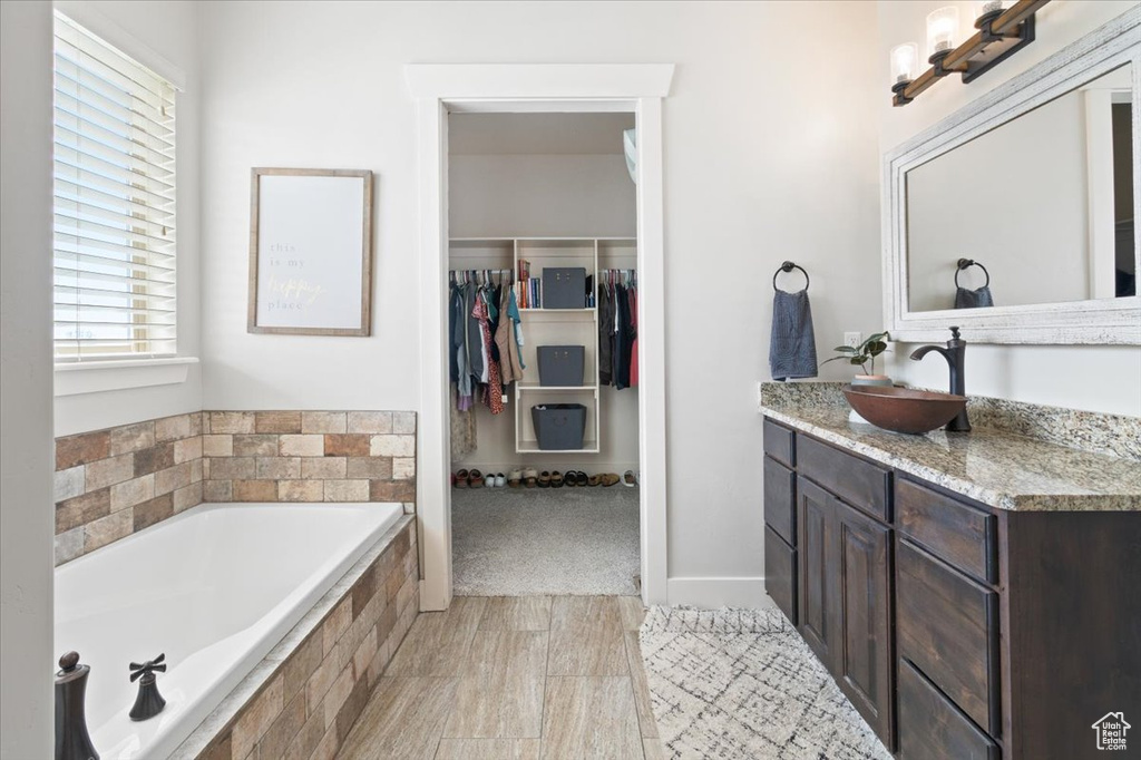 Bathroom featuring tile floors, tiled bath, and vanity