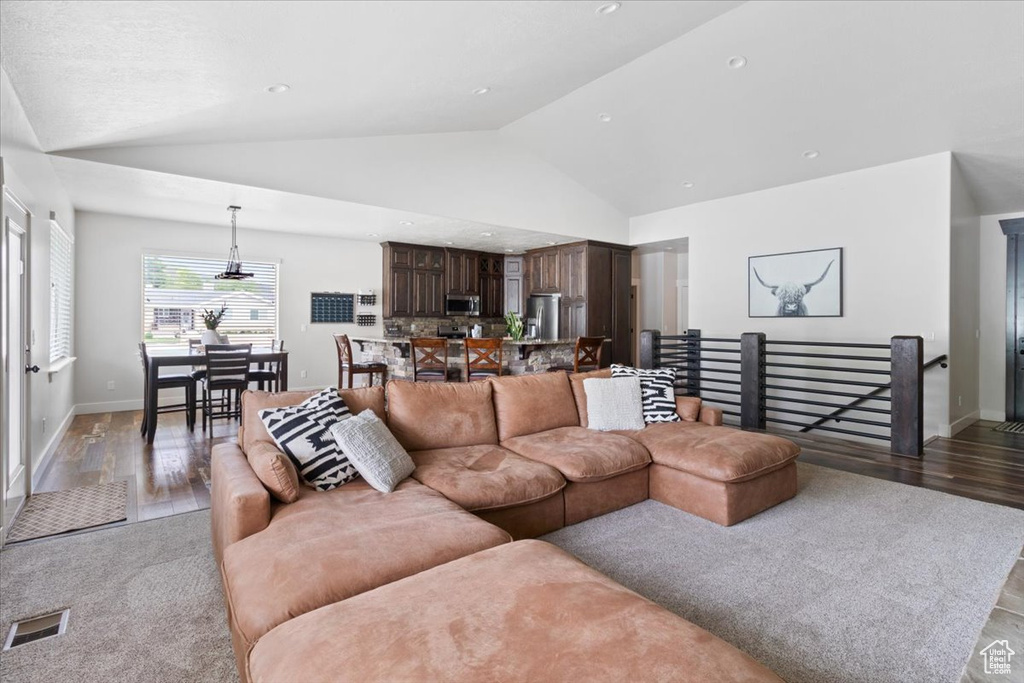 Living room with high vaulted ceiling and hardwood / wood-style flooring