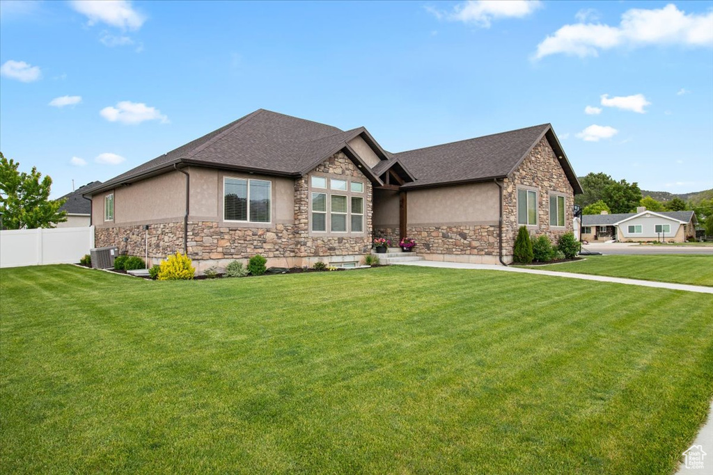 View of front of property with a front yard and central AC unit