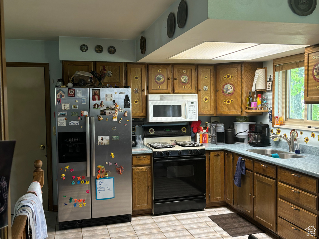 Kitchen with white appliances, sink, and light tile floors