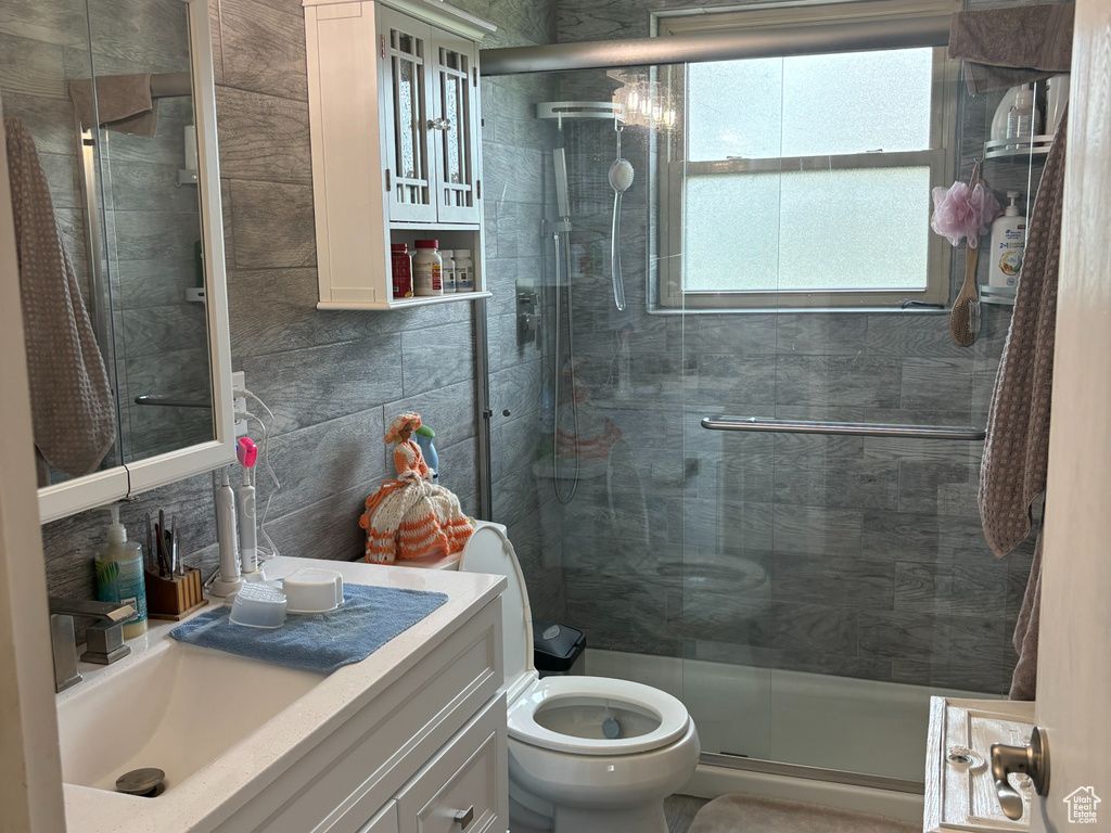 Bathroom with tile walls, toilet, tile flooring, an enclosed shower, and vanity