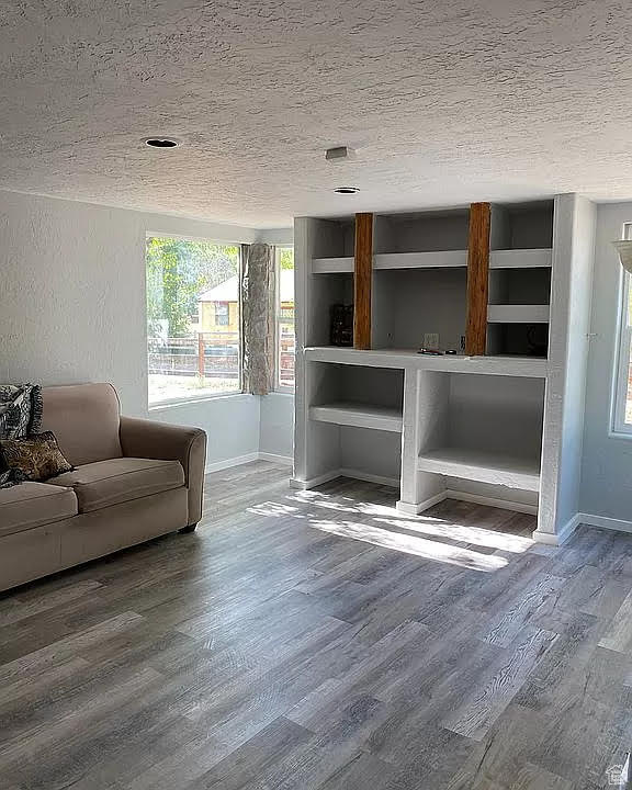 Unfurnished living room featuring a textured ceiling and wood-type flooring