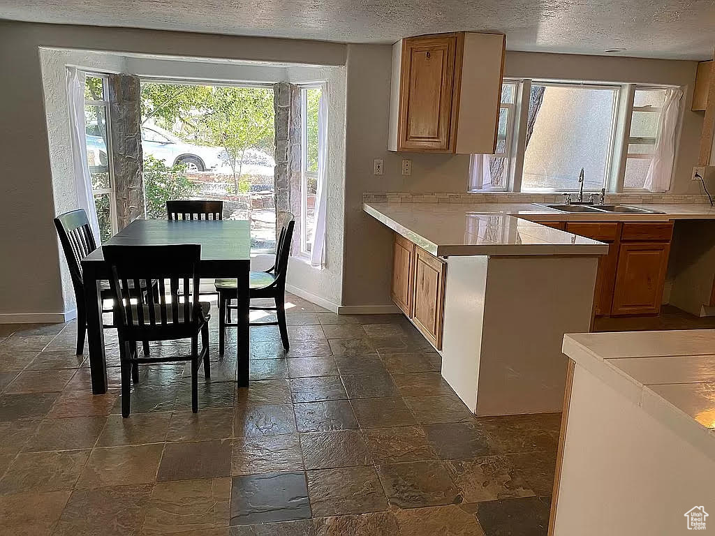 Kitchen with sink, dark tile floors, a textured ceiling, and kitchen peninsula