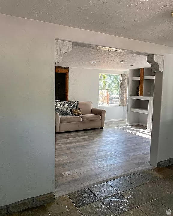 Living room with a textured ceiling and wood-type flooring