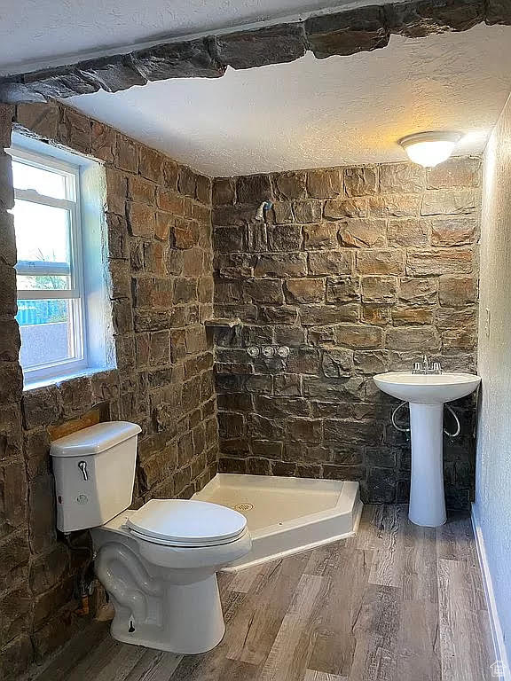 Bathroom with a textured ceiling, a shower, hardwood / wood-style floors, and toilet