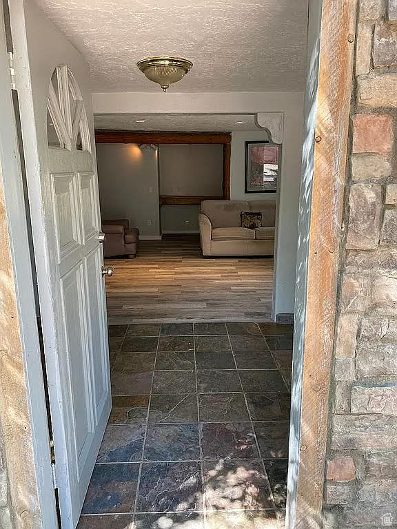 Hall with a textured ceiling and dark tile flooring