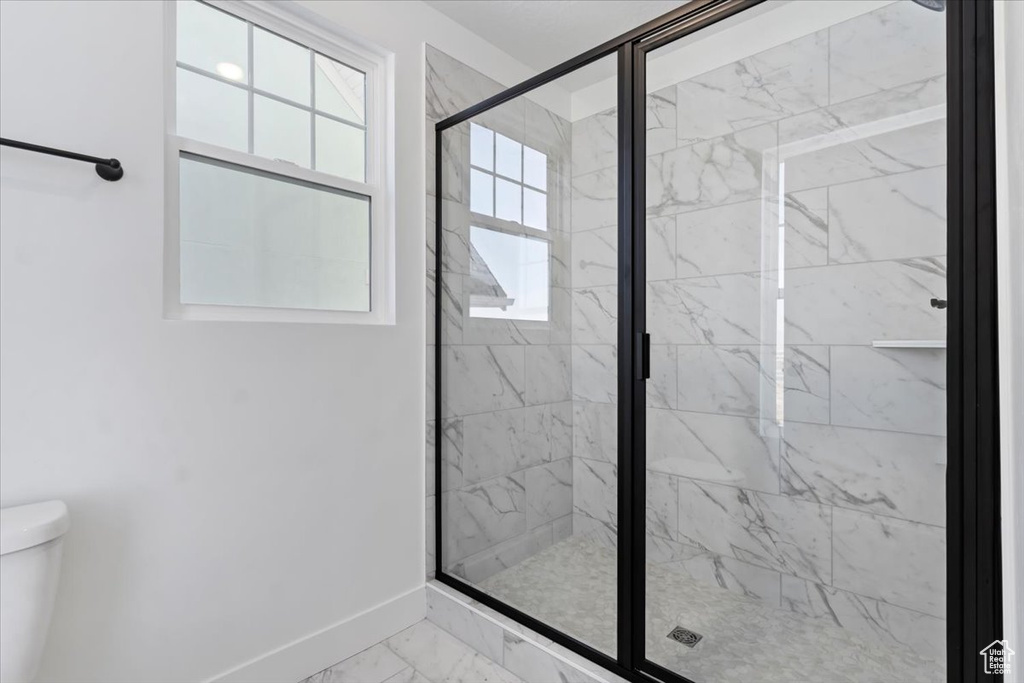 Bathroom featuring a shower with shower door and toilet