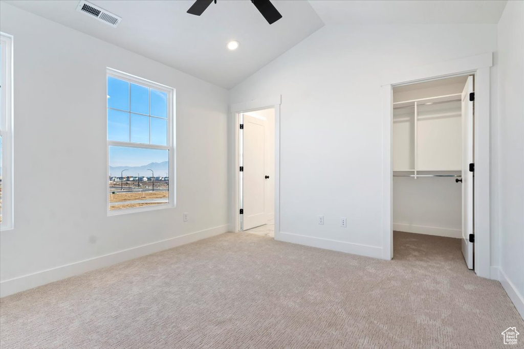 Unfurnished bedroom featuring ceiling fan, lofted ceiling, light carpet, and a closet