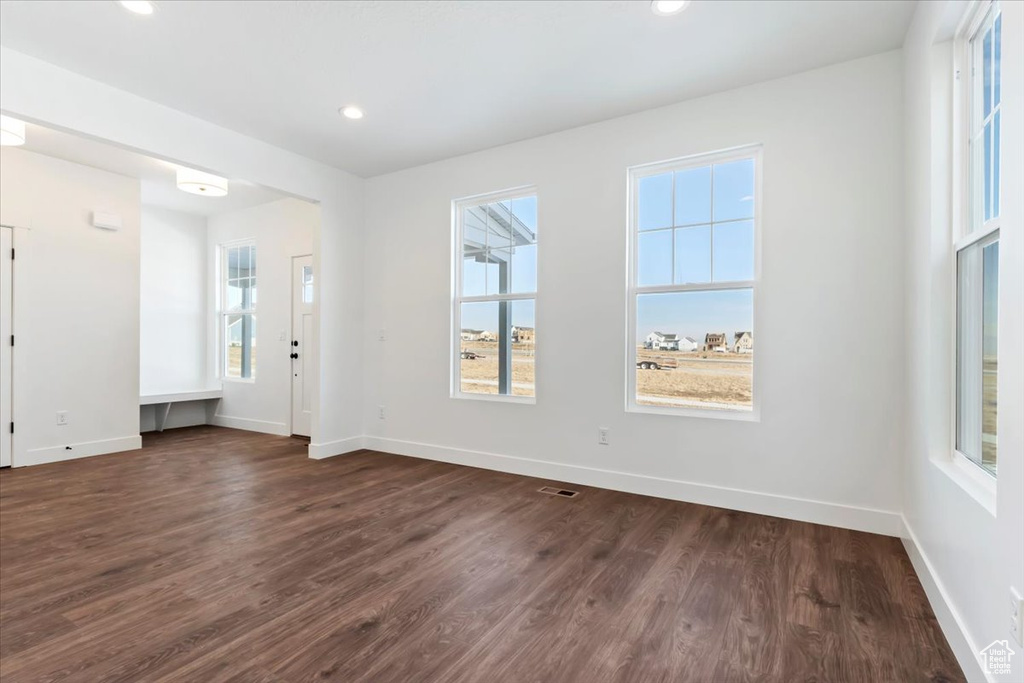 Unfurnished room with dark wood-type flooring and a wealth of natural light