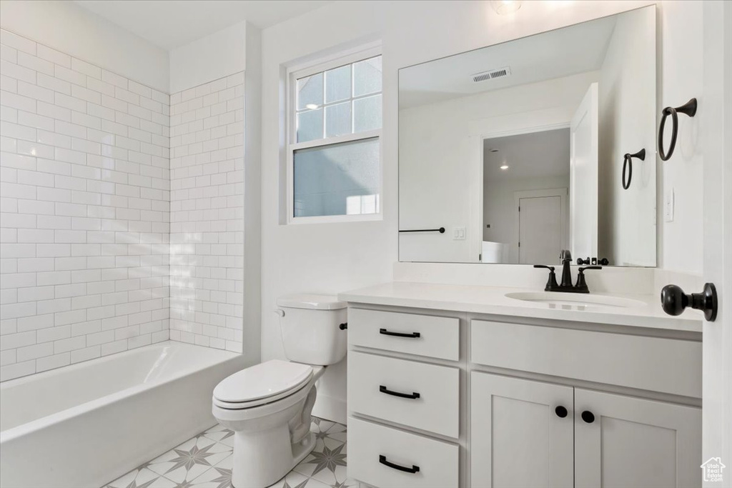 Full bathroom with vanity, toilet, and tiled shower / bath combo