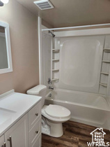 Full bathroom featuring shower / tub combination, hardwood / wood-style flooring, toilet, and vanity with extensive cabinet space