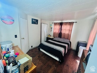 Bedroom with a textured ceiling and dark wood-type flooring