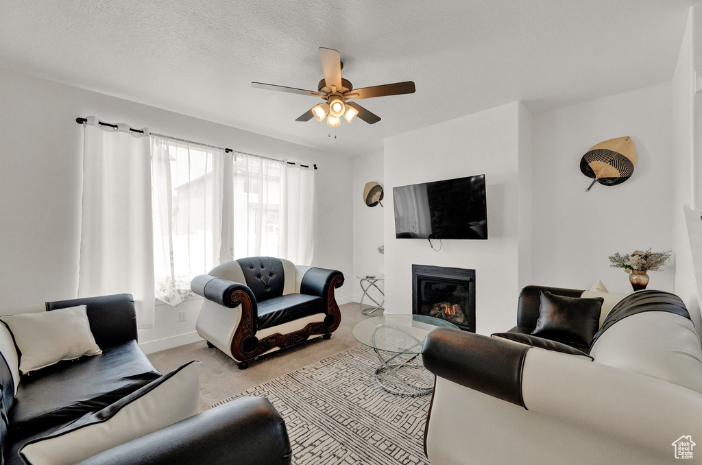 Living room with light colored carpet, ceiling fan, and a textured ceiling