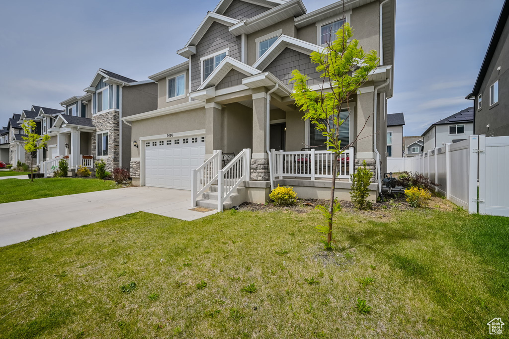 View of front of house featuring covered porch, a garage, and a front lawn