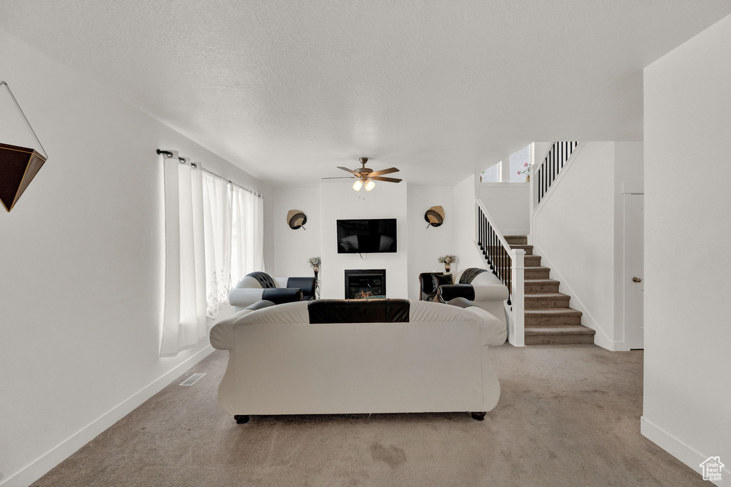 Carpeted living room featuring ceiling fan