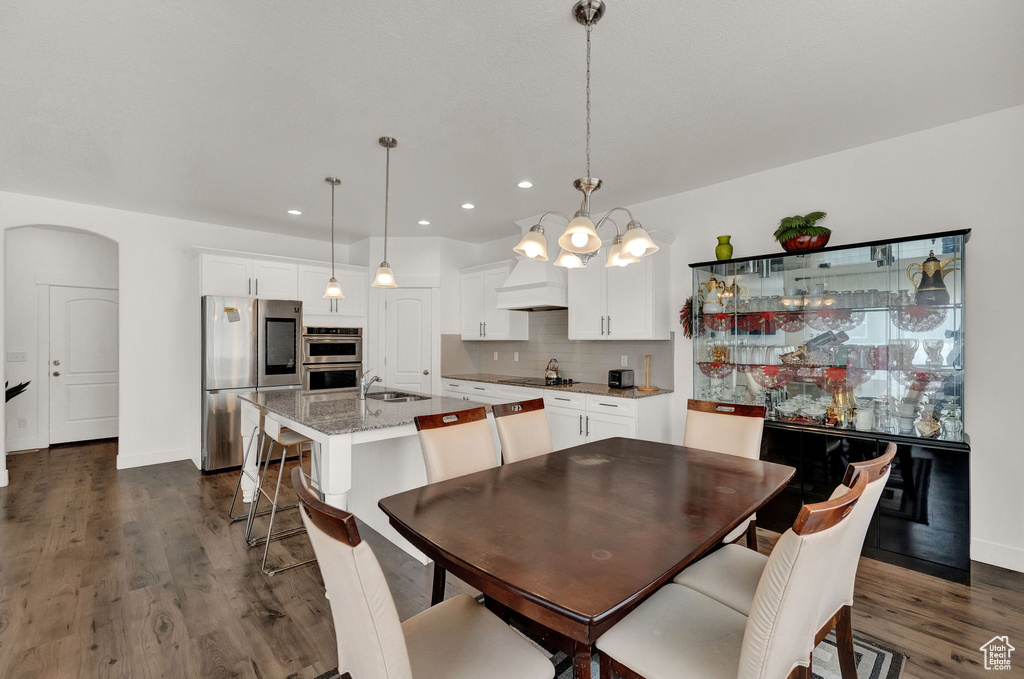 Dining space with sink, dark wood-type flooring, and an inviting chandelier