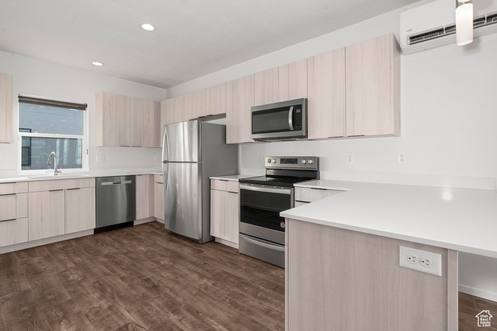 Kitchen featuring dark hardwood / wood-style flooring, appliances with stainless steel finishes, a wall mounted air conditioner, sink, and light brown cabinetry