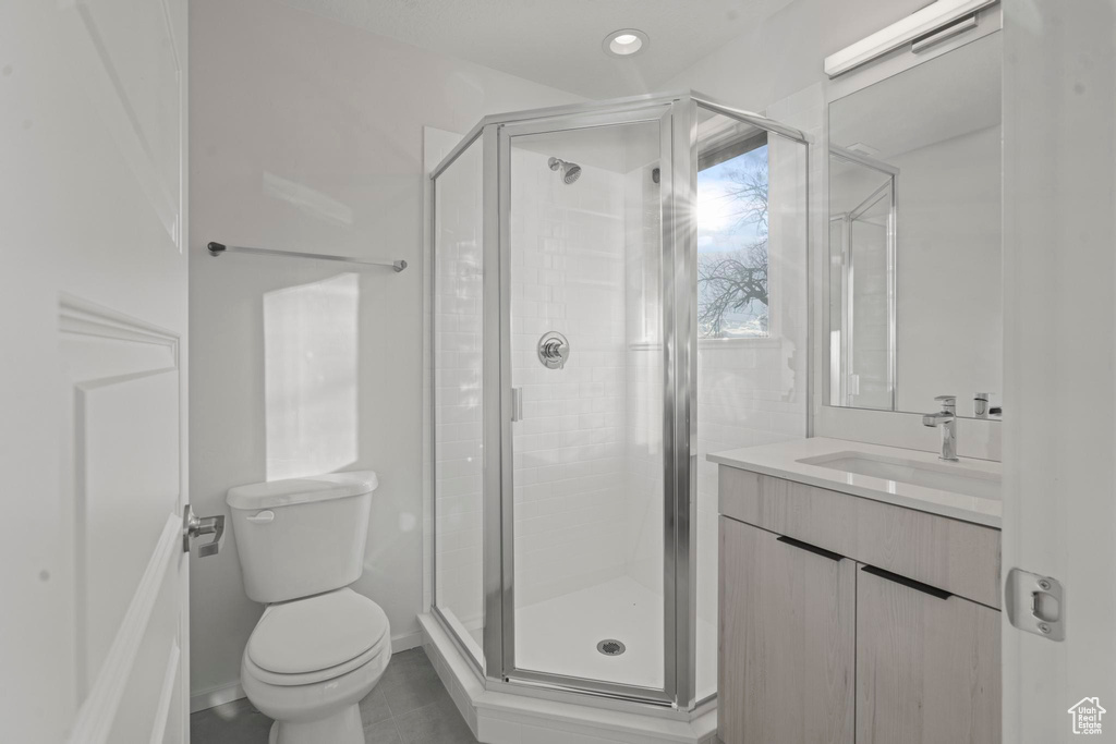 Bathroom featuring walk in shower, tile flooring, toilet, and vanity with extensive cabinet space