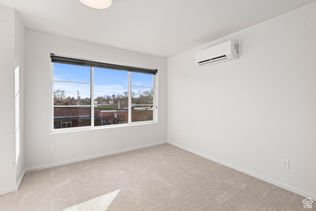 Empty room with carpet flooring and a wall unit AC