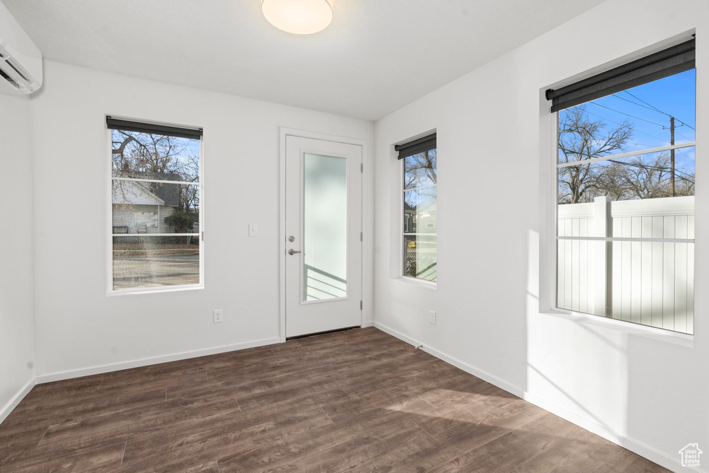 Spare room with a wall unit AC and dark hardwood / wood-style floors