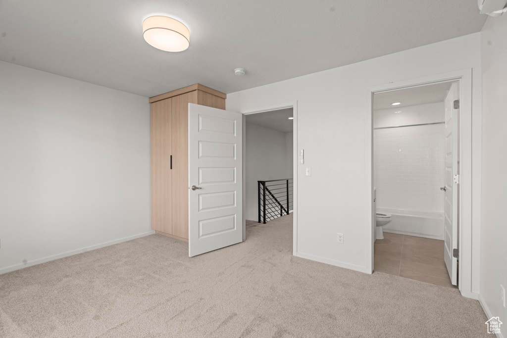 Unfurnished bedroom featuring connected bathroom and light carpet