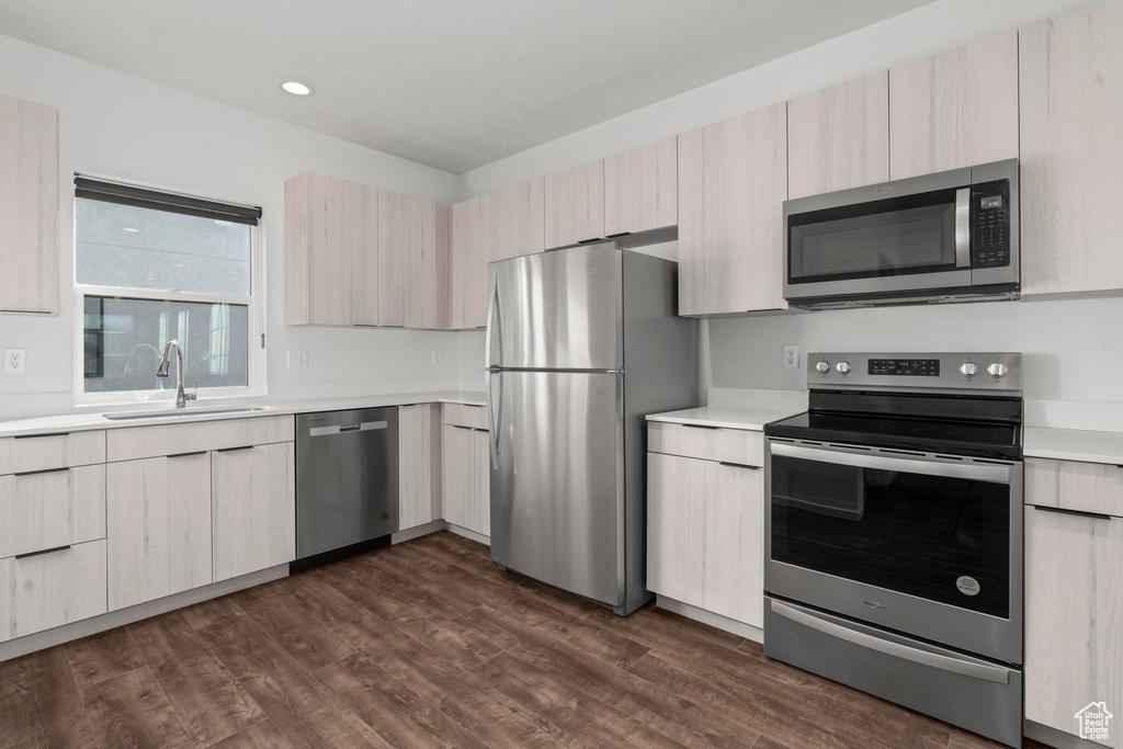 Kitchen with appliances with stainless steel finishes, sink, dark hardwood / wood-style floors, and light brown cabinetry