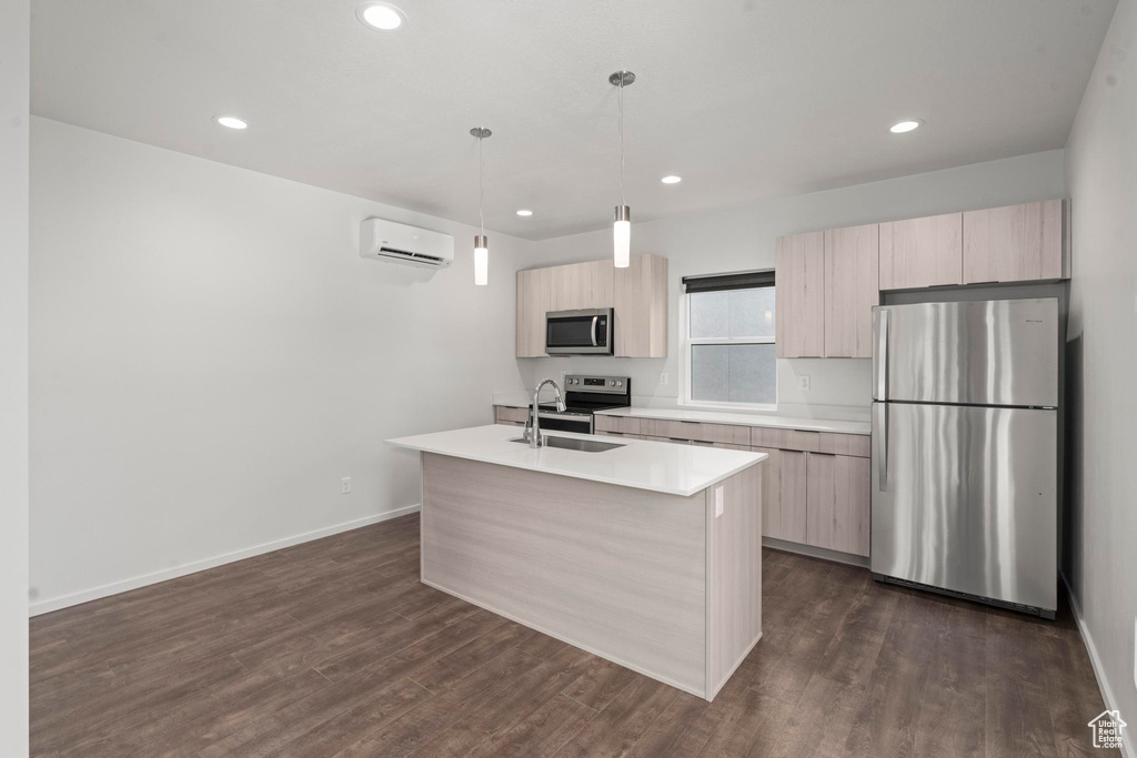 Kitchen with an AC wall unit, a center island with sink, dark wood-type flooring, appliances with stainless steel finishes, and sink