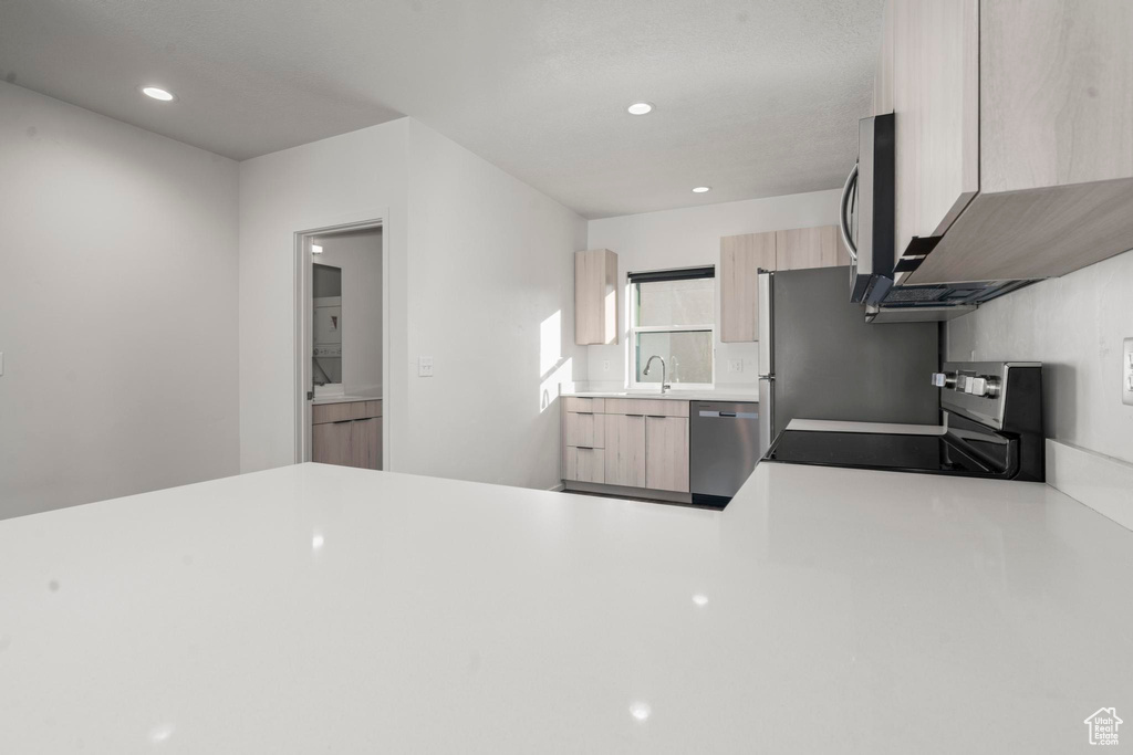 Kitchen featuring light brown cabinets, stainless steel appliances, and sink