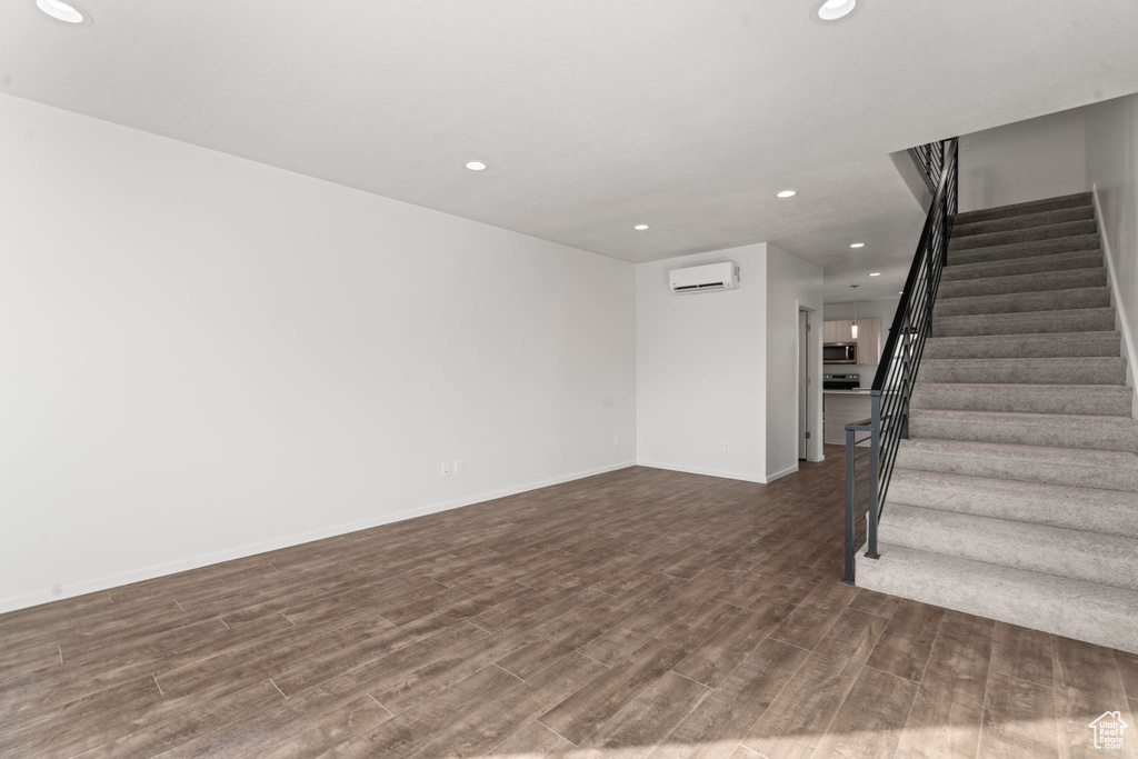 Unfurnished living room with a wall mounted AC and dark hardwood / wood-style floors