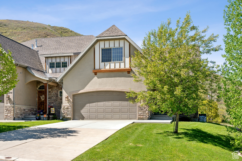 Tudor home featuring a garage, a mountain view, and a front lawn