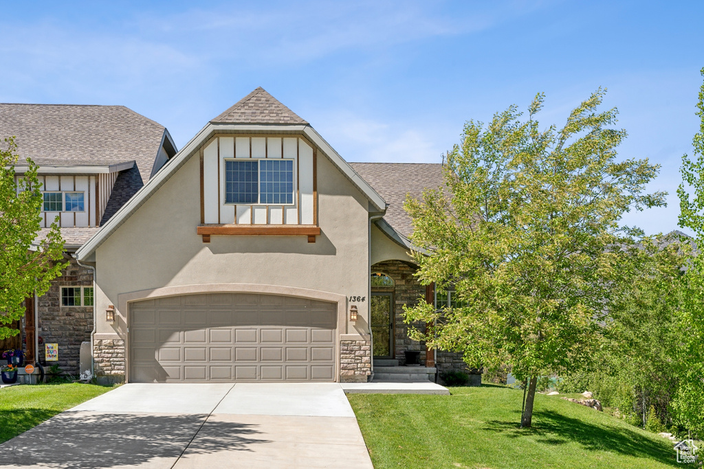 Tudor house featuring a garage and a front lawn