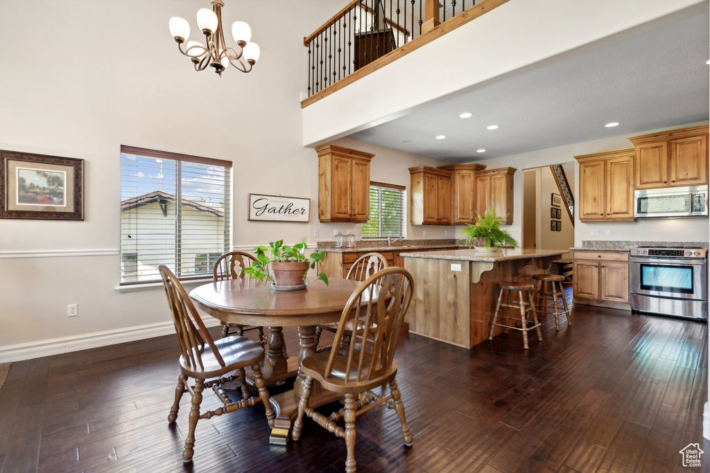 Dining space with dark wood-type flooring, a high ceiling, and a chandelier