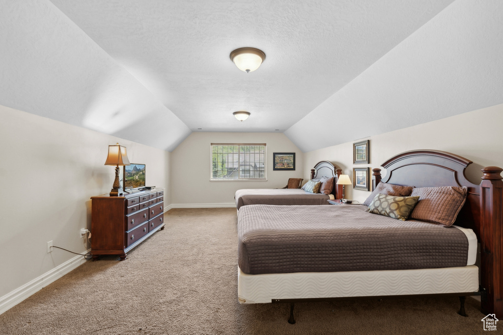 Carpeted bedroom featuring a textured ceiling and lofted ceiling