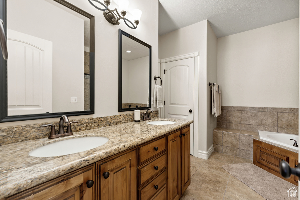 Bathroom with dual sinks, tile flooring, a bathing tub, a textured ceiling, and large vanity