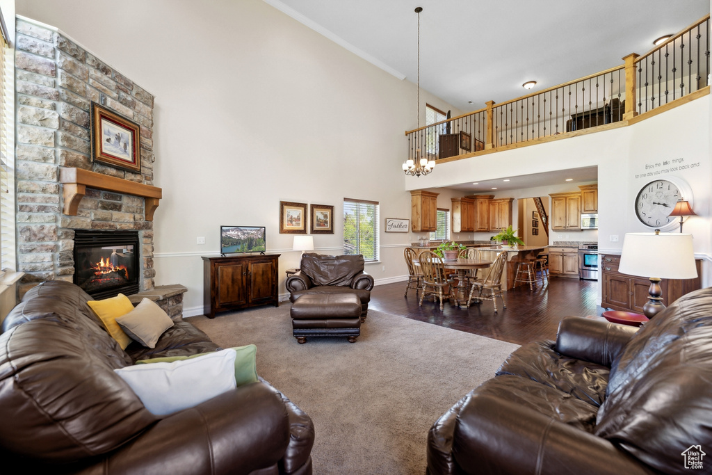 Living room with crown molding, a fireplace, dark hardwood / wood-style floors, a chandelier, and a towering ceiling