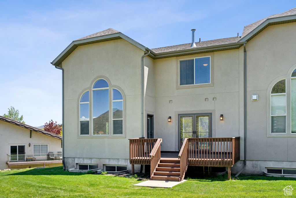 Rear view of house featuring a wooden deck and a yard